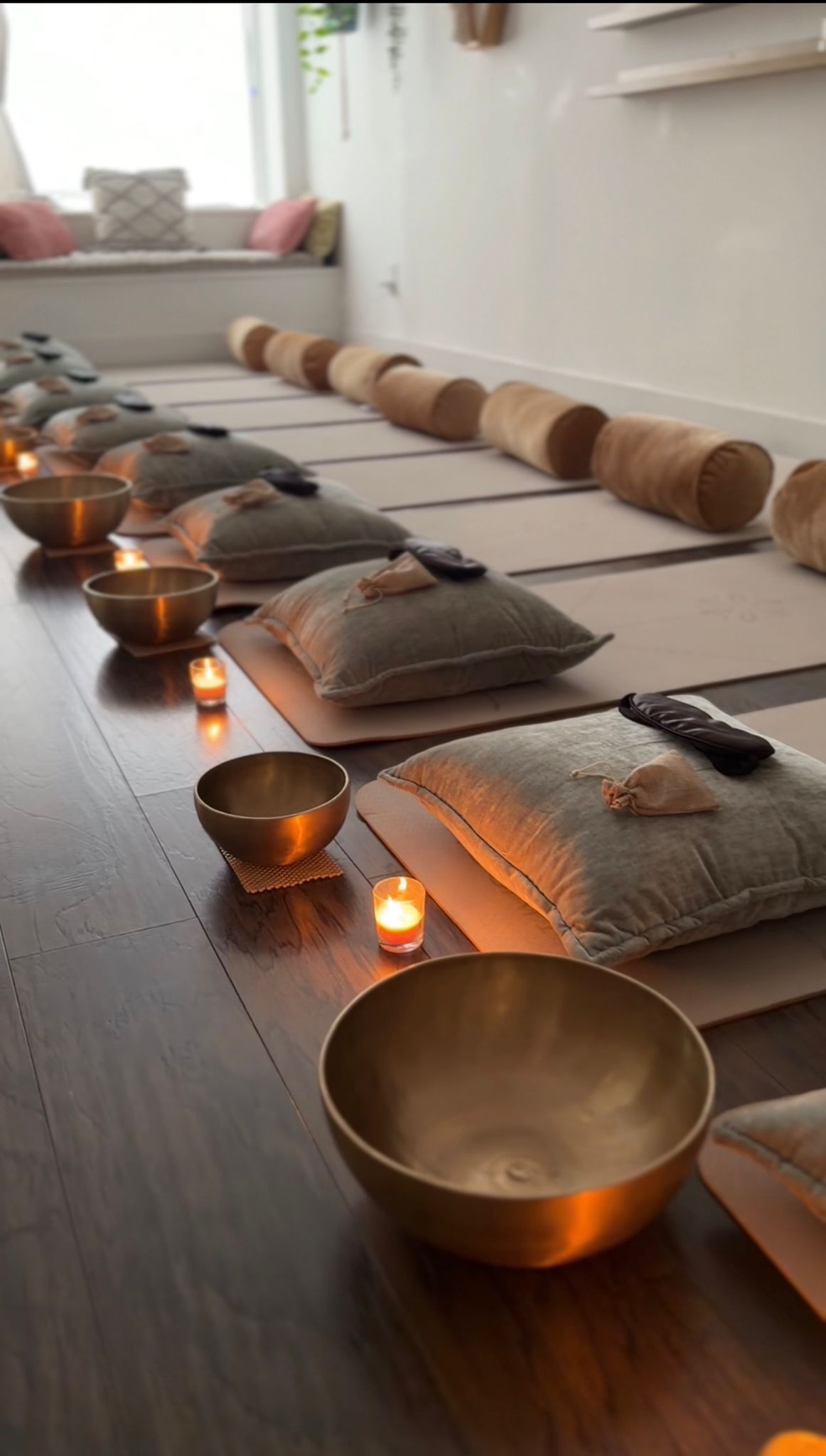 Singing bowls, candles and bolsters laid out before a session